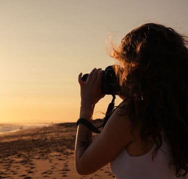a woman taking a picture of a sunset