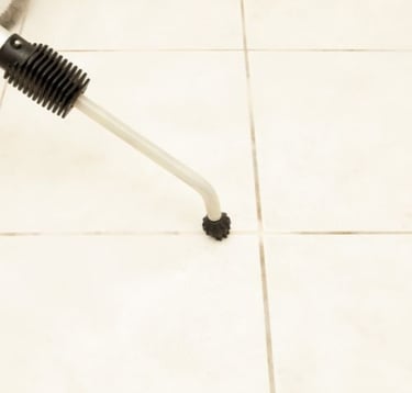 cleaning a tile floor with a brush/wand