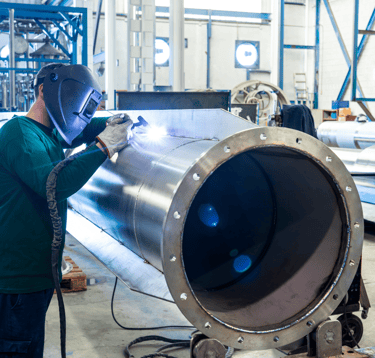 a man in a welding helmet welding a stainless steel pipe