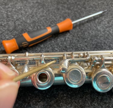 gros plan sur une main tenant un outils pour entretenir une flûte traversière