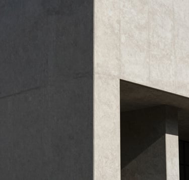 A minimalist photograph of an urban architectural detail in a US city, featuring sharp shadows and neutral concrete textures that mirror the artist's abstract realism style, editorial lighting.
