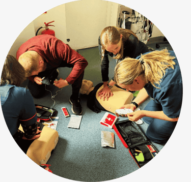 A group of learners completing practical CPR and AED training with manikins