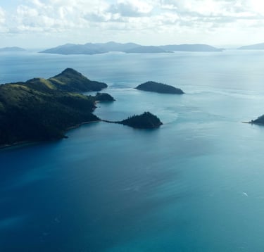 Aerial view of tropical islands and blue ocean water in the Whitsundays, Australia.