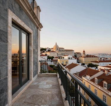 An elegant, low-angle shot of a luxury penthouse balcony overlooking the historic skyline of Lisbon at dusk. The setting features slate grey stone and soft champagne gold lighting, reflecting a European / International High-Net-Worth lifestyle of exclusivity.