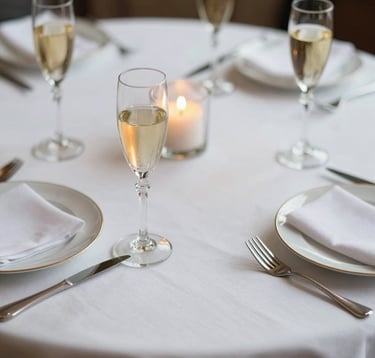 Close-up of a meticulously set table at a private social club in Madrid. Crisp white linen, fine crystal glassware reflecting champagne gold candlelight. Understated elegance, reflecting a European / International High-Net-Worth lifestyle.