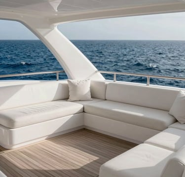 A high-end photography of a private yacht deck at sea, with elegant white furnishings and a glimpse of the deep blue ocean. North American / International luxury aesthetic with soft light grey tones.