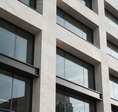 Close-up architectural detail of a premium modern building facade in Israel, showcasing high-quality stone and glass. Sharp lines and minimalist aesthetic, captured in soft daylight with a focus on luxury textures in white and grey materials.