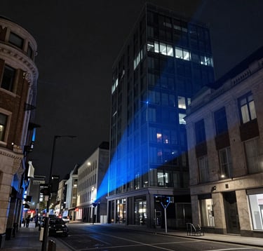 A complex LiDAR laser scanning point cloud representing a modern street in a European / British city, rendered in electric blue and dark slate grey on a deep charcoal black background. High-tech industrial aesthetic.