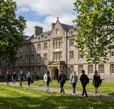 A photography prompt showing a lush green university campus in Dublin, Ireland. A group of students is seen walking near a historic stone building during a sunny afternoon excursion. The mood is safe, welcoming, and academic. North American / US style photography.