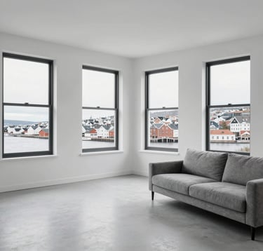 A spacious, minimalist living room with white walls and large black-framed windows showing a Northern European city view. The interior features a grey sofa and professional, clean lighting.