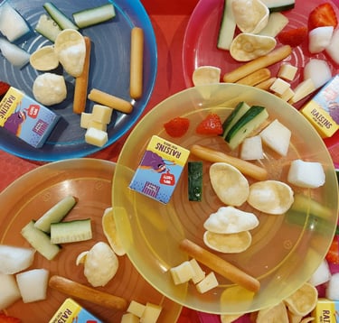 Children’s snack plates at Newport Playgroup Saffron Walden fruit, cucumber, crackers & raisins at toddler group snack time