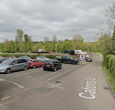 Free parking at Saffron Walden Town Football Club on Catons Lane, with the entrance lane visible and cars parked in car park.