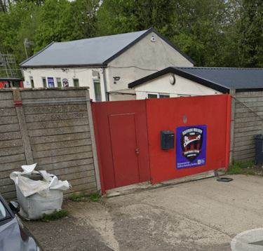 Entrance gate to Saffron Walden Town Football Club on Catons Lane, showing the red gate & access to the venue.