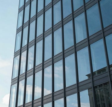 An abstract, high-contrast photograph of a professional glass building architecture reflecting a clear blue sky. The composition is geometric and sharp, symbolizing clarity and structure. Colors: Soft Sky Grey and Slate Steel Blue.
