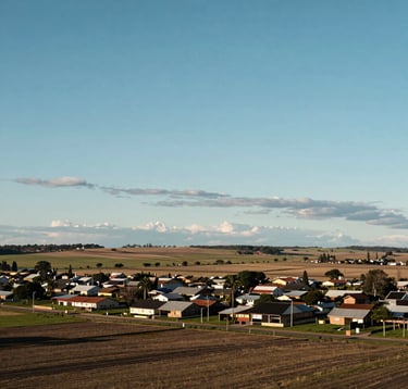 A wide-angle landscape shot of fertile agricultural land or a spacious suburban lot in Capitán Bermúdez. Blue sky with soft clouds, conveying opportunity and peace. South American / Argentinian countryside.