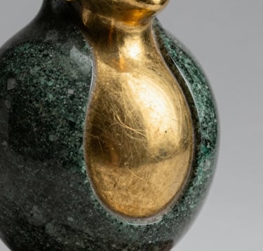 Macro photography of a sophisticated sculpture made of dark green stone and polished gold, reflecting a soft light in a professional Brazilian studio setting. Luxurious and refined aesthetic.