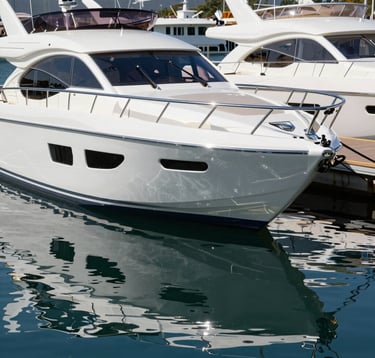 A high-gloss white luxury motor yacht docked at a premium North American marina. The shot focuses on the sleek lines and professional marine paint finish, with reflections of clear blue water.