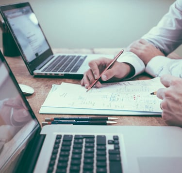 A person working on a paper, presenting to another person.