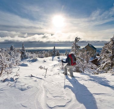 Randonneur en raquettes explorant les paysages enneigés des Monts-Valin à la SEPAQ, profitant de la beauté naturelle et de l'