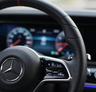 Close-up macro photography of a leather steering wheel and a modern digital dashboard with blue glowing interfaces, luxury car interior, soft bokeh, professional lighting, European aesthetic.