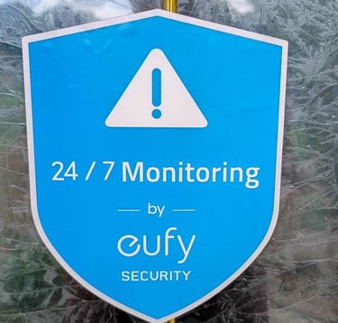 Eufy Security window decal showing 24/7 monitoring services on a blue shield logo.