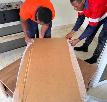 Two professional movers in orange high-visibility shirts with reflective stripes and blue accents co