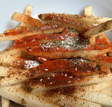 Raw potatoes with seasoning dumped ontop, not mixed yet. See ingredients list for details.