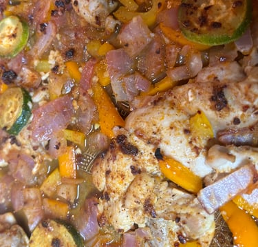 Baked chicken and vegetables on a baking pan just out of the oven.