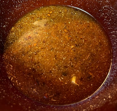 Brown sauce in a bowl full of spices and liquid.