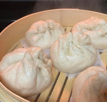Steamed dumplings in bamboo steamer with steam rising. For FlavorfulBites