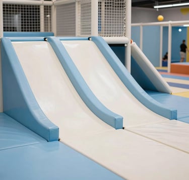A close-up of a modern, high-standard soft play area in a Bulgarian amusement park. The equipment is clean, featuring light blue and off-white safety padding. The lighting is natural and inviting, emphasizing a professional and secure space.