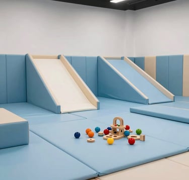 A safe and clean indoor soft play area for toddlers with padded floor mats in light blue. Educational wooden toys are neatly placed. The lighting is bright and soft, highlighting the trustworthy and professional environment of the park.