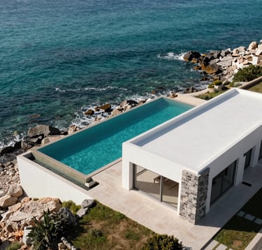 An aerial photography shot of a coastal luxury property on the Spanish-speaking / Iberian Peninsula coast, featuring a private infinity pool blending with the turquoise sea. The architecture is minimalist with clean white surfaces and gray stone accents, captured in high-contrast morning sunlight.