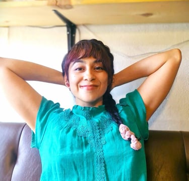 Mujer sentada en un sillon, tomandose un momento para relajarse con las manos en su nuca. 