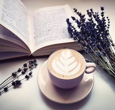 a cup of coffee with a book and a bouquet of flowers