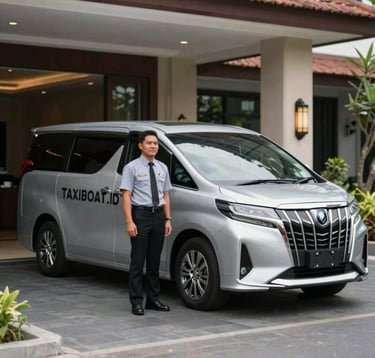 A professional chauffeur standing next to a clean, modern silver transport van at a Balinese hotel entrance. The driver is dressed professionally, representing the reliable airport and hotel transfer services offered by TAXIBOAT.ID. Soft daylight, clean composition.