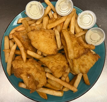 Golden crispy fried fish fillets served with French fries and four cups of tartar sauce on a blue plate.