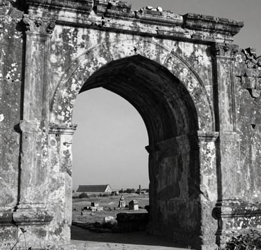 A high-contrast, black and white photograph focusing on the weathered texture of an ancient stone archway in a distant land. The play of light and shadow emphasizes the age and wisdom of the structure, evoking a sense of deep cultural exploration.