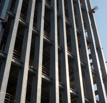 A dynamic shot of a commercial construction site in a US metro area, featuring vertical steel beams of a skyscraper reaching into the air, with high-contrast shadows and sharp industrial lines.