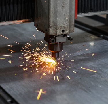 Close-up action shot of a CNC laser cutting through heavy steel plate. Bright orange sparks spray across the dark gray metal surface. The focus is sharp on the cutting head, showcasing high-precision modern technology.