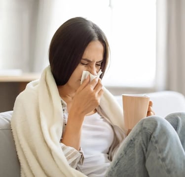 Young woman sitting in a sofa sneezing and drinking coffee