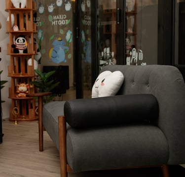 Modern dental clinic reception area with comfortable couches, tooth-shaped pillows, and a sleek wood