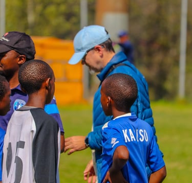 a man in a blue shirt is talking to a group of young boys