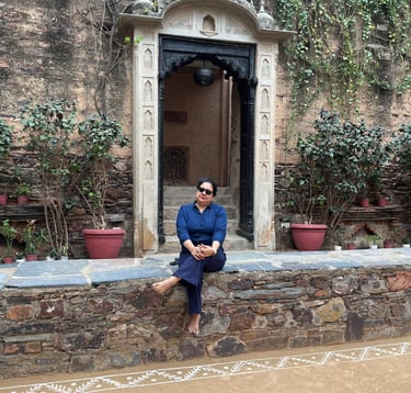 a woman sitting on a stone wall with a door open