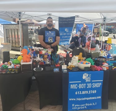 Mic-Bot standing in front of a table with a display of 3D Models