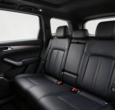 Close-up interior photography of a luxury vehicle cabin in Oceania / New Zealand. Focus on the high-quality dark leather upholstery and spacious legroom, conveying a sense of understated luxury and serene comfort.