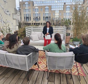 Groupe d’élèves assis sur une terrasse, suivant une formation dirigée par une formatrice .