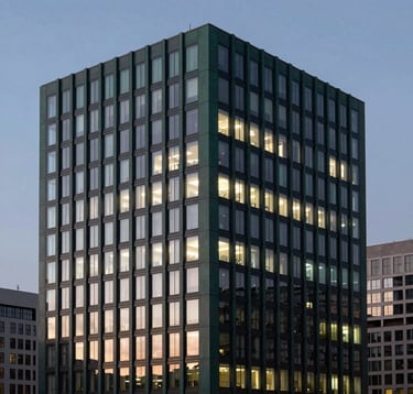 A professional architectural photograph of a modern financial district building at dusk. The building reflects deep forest green and charcoal grey tones, with soft off-white lights glowing from the windows, symbolizing stability.