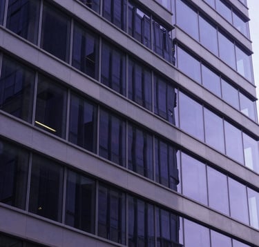 Abstract photography of a modern architectural structure with glass and metal reflecting deep navy and purple light. The composition is clean and sharp, conveying stability and scalable growth. North American / US corporate setting.