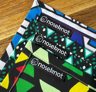 Three vibrant Noseknot handkerchiefs showing the stitching, corners and Noseknot labels